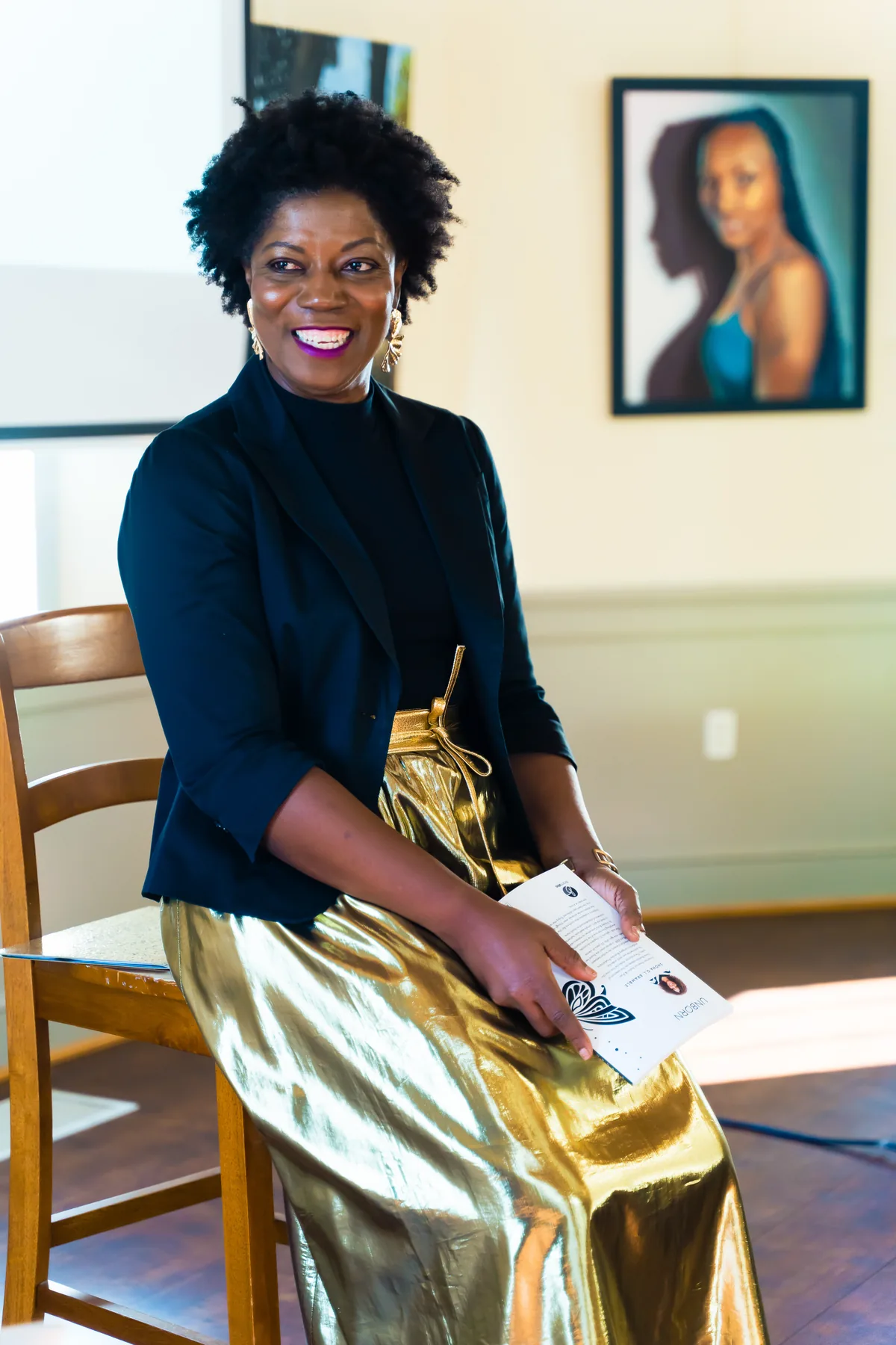 Shona Bramble seated, holding a copy of her poetry collection Unborn.